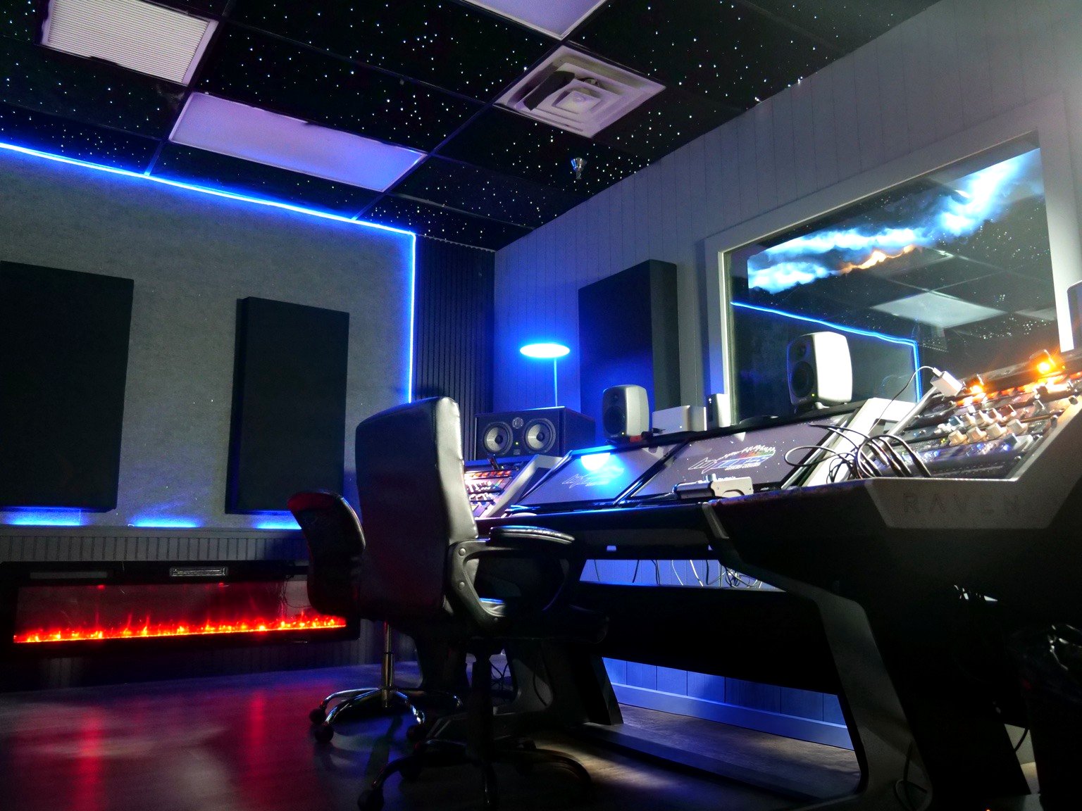 A wide angle view of the Hi-Tunes Studio Premium Room's Raven workstation, fiber-optic star ceiling, blue accent lighting, and fireplace.